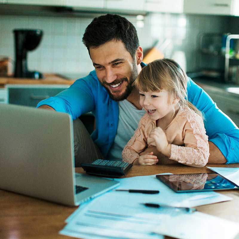 father and daughter smiling while looking in their screen